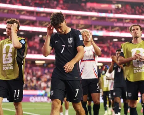 Giovanni Reyna and USA teammates in black uniforms hold their heads in disappointment on field