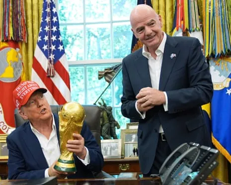 Donald Trump holds a trophy in the Oval Office next to Fifa president Gianni Infantino.